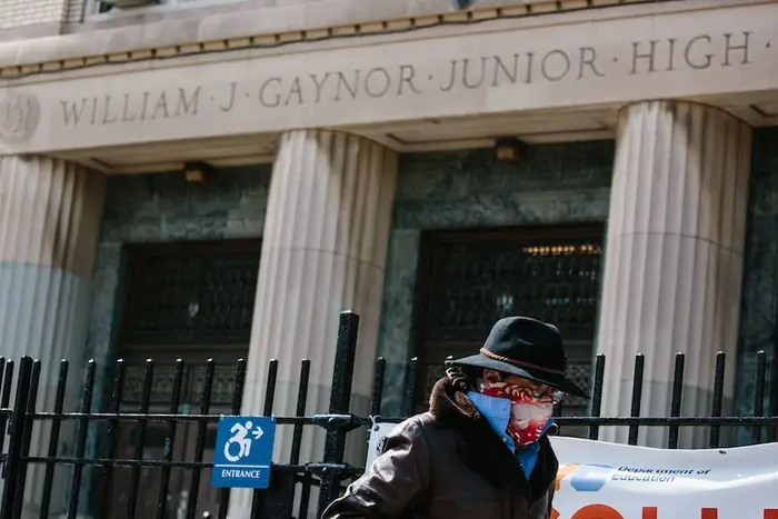 A man in a mask walks past the shuttered William J. Gaynor Junior High School in Brooklyn.